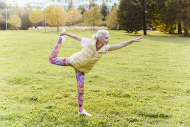 Ältere Frau macht Yoga-Übungen auf Gras in einem öffentlichen Park - VYF00358