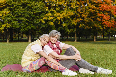 Ältere Frau ruht mit geschlossenen Augen auf der Schulter einer Freundin in einem öffentlichen Park - VYF00367