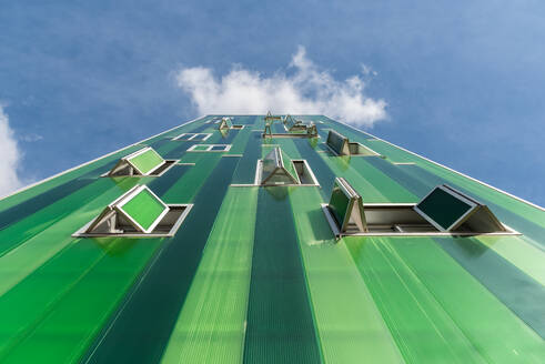 From below contemporary building with vivid green facade and opened windows on blue sky - ADSF19197