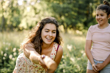 Lächelndes Mädchen schaut auf Teenager-Geschwister beim Spielen molkky im Hinterhof - MASF20945