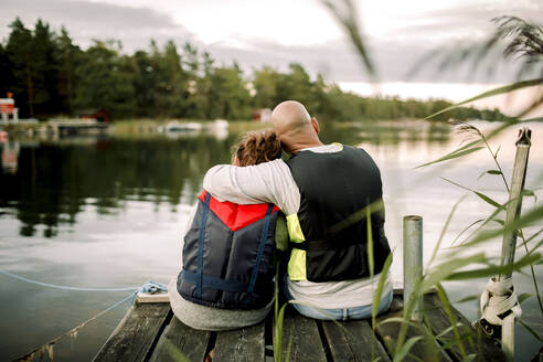 Vater und Tochter sitzen auf einem Steg am See - MASF20951