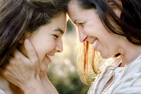 Lächelnde Mutter umarmt Tochter im Garten - MASF20956