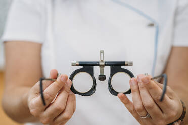 Female optometrist holding eye checking glasses at hospital - MPPF01303