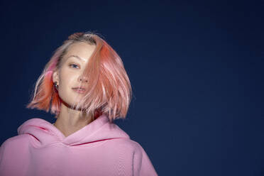 Portrait of young woman with pink hair wearing pink hooded shirt at dusk - VPIF03306