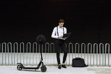 Stylish businessman working on laptop in city - XLGF00850