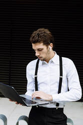 Stylish businessman working on laptop in city - XLGF00853