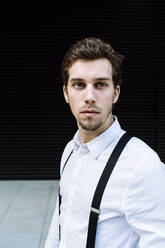 Portrait of stylish businessman wearing white shirt and black suspenders - XLGF00856