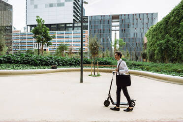 Geschäftsmann mit Elektro-Scooter in der Stadt - XLGF00859