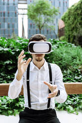 Businessman wearing virtual reality goggles outdoors - XLGF00869