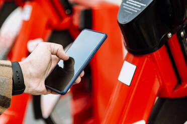 Mans Hand hält Smartphone, um Fahrrad zu mieten - XLGF00883