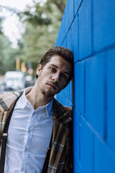 Portrait of stylish man leaning against blue wall - XLGF00889