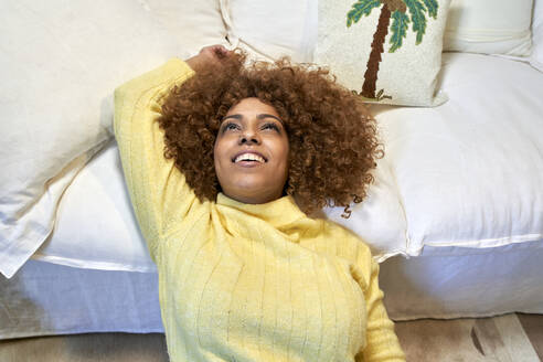 Smiling woman leaning on sofa after work in living room - VEGF03314