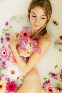 Beautiful woman looking away while taking bath in beauty spa - GMLF00906