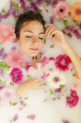 Junge Frau entspannt sich mit geschlossenen Augen in einer Badewanne im Spa - GMLF00912
