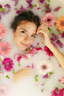 Smiling woman relaxing in bathtub at beauty spa - GMLF00913