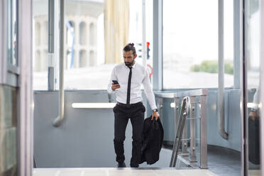 Geschäftsmann geht mit Smartphone in der Hand eine Treppe hinauf - JCCMF00222