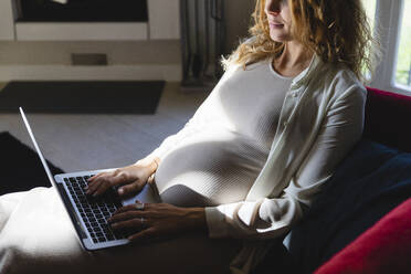 Businesswoman working on laptop at home - MRAF00594