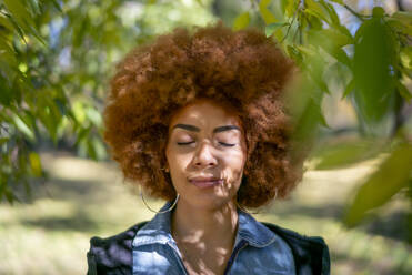 Schöne Frau mit geschlossenen Augen in einem öffentlichen Park an einem sonnigen Tag - OCMF01863