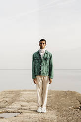 Young man standing on pier against sea - AFVF07851