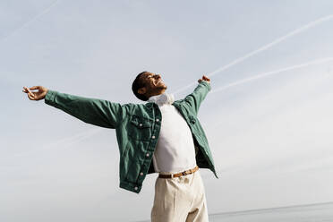 Happy carefree man with arms outstretched against sky - AFVF07855