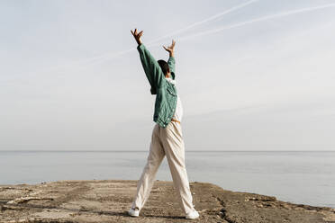 Junger Mann tanzt auf Pier vor Himmel und Meer - AFVF07857