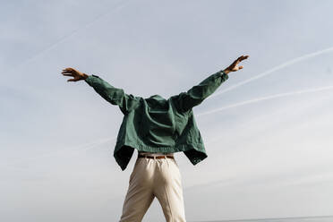 Young man with arms outstretched dancing against sky - AFVF07858