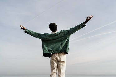 Young man with arms outstretched against sky - AFVF07860