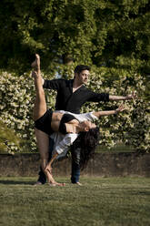 Heterosexual couple dancing with elegance in back yard during - MAUF03669