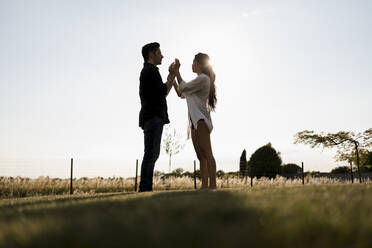 Affectionate dancing couple in field on sunny day - MAUF03672