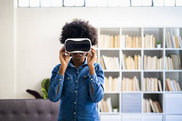 Woman using virtual reality headset while standing at home - GIOF10000