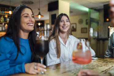 Lächelnde Freundinnen, die in einer Bar Getränke genießen - EGAF01278
