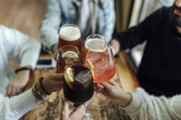 Friends hands toasting glasses at bar - EGAF01281