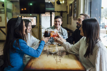 Smiling friends toasting drinks over table in bar - EGAF01284