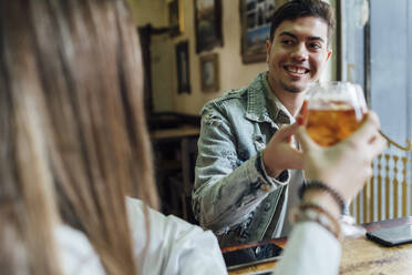 Glückliche Freunde, die lächelnd in einer Bar auf ein Getränk anstoßen - EGAF01286