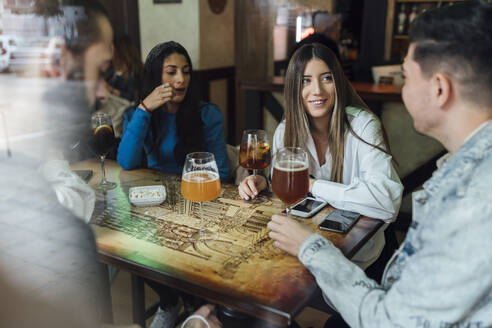 Männliche und weibliche Freunde unterhalten sich bei einem Drink im Restaurant - EGAF01288