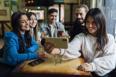 Lächelnde Freunde nehmen Selfie auf Smartphone in Bar - EGAF01289