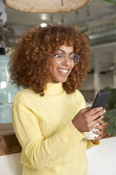 Smiling woman using smart phone in coffee shop - VEGF03329