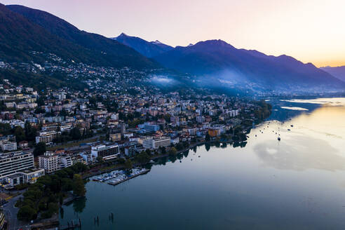 Schweiz, Kanton Tessin, Locarno, Blick aus dem Hubschrauber auf die Stadt am Ufer des Lago Maggiore in der Morgendämmerung - AMF08871