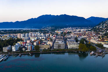 Switzerland, Canton of Ticino, Locarno, Helicopter view of town on shore of Lake Maggiore at dawn - AMF08872