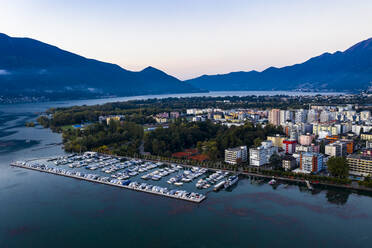 Switzerland, Canton of Ticino, Locarno, Helicopter view of harbor of lakeshore town at dawn - AMF08873