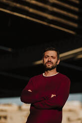 Man standing with arms crossed outdoors - GMLF00921