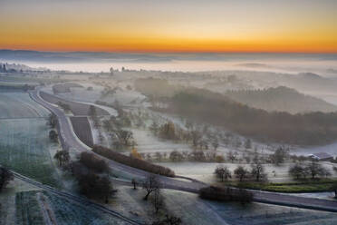 Germany, Baden-Wurttemberg, Berglen, Drone view of countryside road at foggy autumn dawn - STSF02733