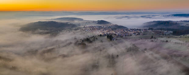 Deutschland, Baden-Württemberg, Berglen, Drohnenansicht eines in dichten Nebel gehüllten Dorfes in der Morgendämmerung - STSF02737