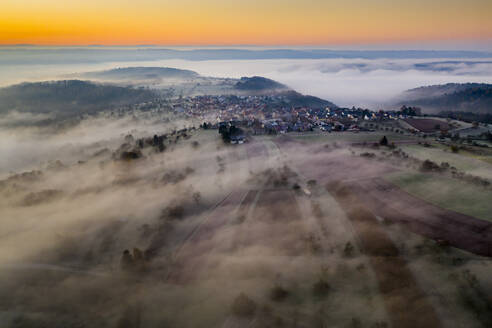 Deutschland, Baden-Württemberg, Berglen, Drohnenansicht eines in dichten Nebel gehüllten Dorfes in der Morgendämmerung - STSF02738