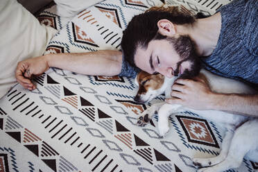 Man sleeping with dog on bed at home - EBBF01841