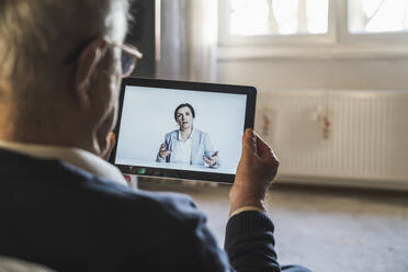 Female doctor consulting male patient on video call through digital tablet at home - UUF22270