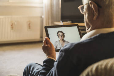 Ein älterer männlicher Patient lässt sich von einer Ärztin für Allgemeinmedizin per Videoanruf über ein digitales Tablet beraten - UUF22275