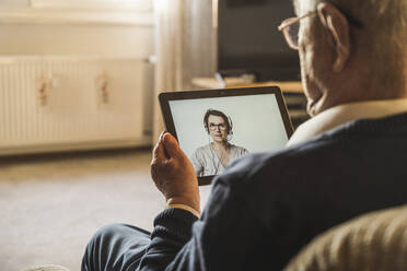 Senior male patient taking advice from female general practitioner on video call through digital tablet - UUF22275