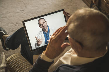 Elderly man talking with male doctor on video call at home - UUF22279