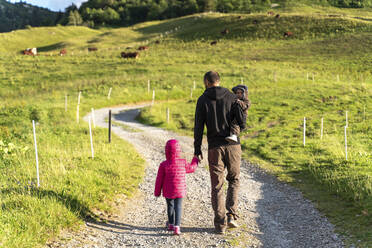 Vater geht mit zwei Kindern auf dem Wanderweg des Col des Aravis, Haute-Savoie an einem sonnigen Tag, Frankreich - GEMF04471